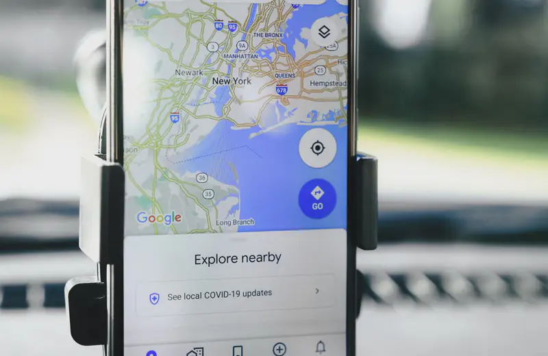Móvil con Google Maps abierto en el salpicadero de un coche buscando negocios cercanos