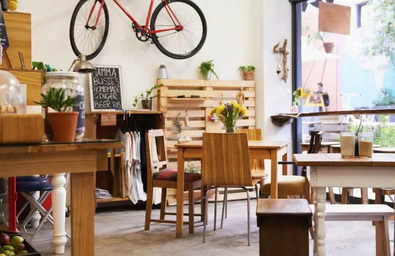 Interior de un pequeño negocio local con bicicleta colgada y mesas de madera