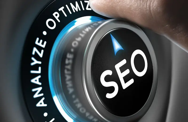 Mano girando un dial con la palabra SEO entre las opciones analizar, optimizar y reportar